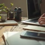 Bureau en bois avec ordinateur portable, plante, tasse et smartphone
